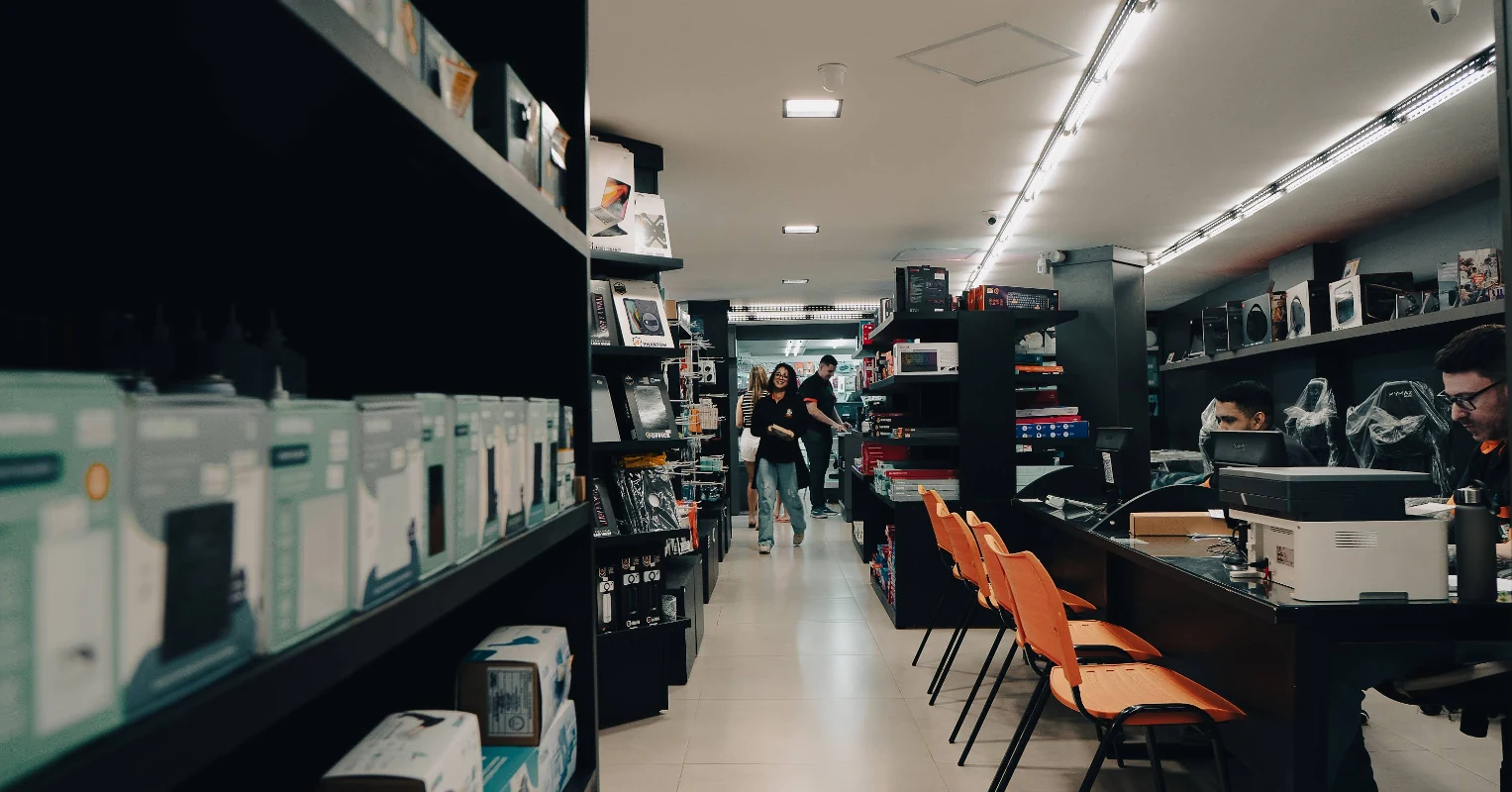 Interior da Casa do Computador em Muriaé, com prateleiras de produtos, balcão de atendimento e pessoas na loja